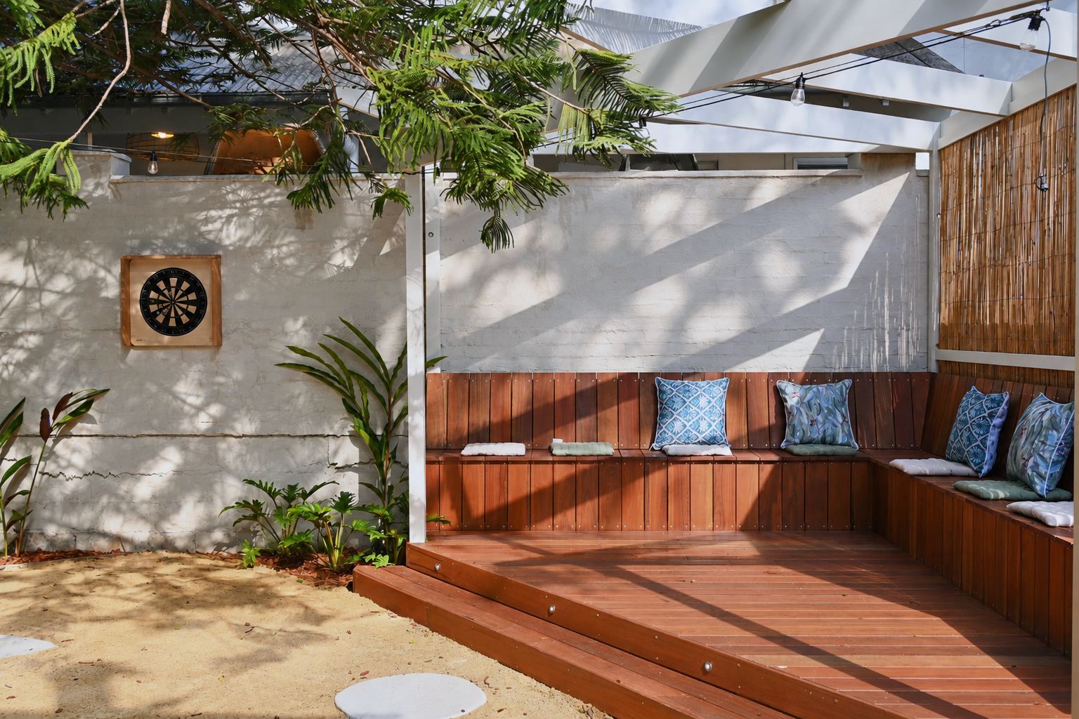 Built-in timber banquette with cushions and a dartboard in the back garden