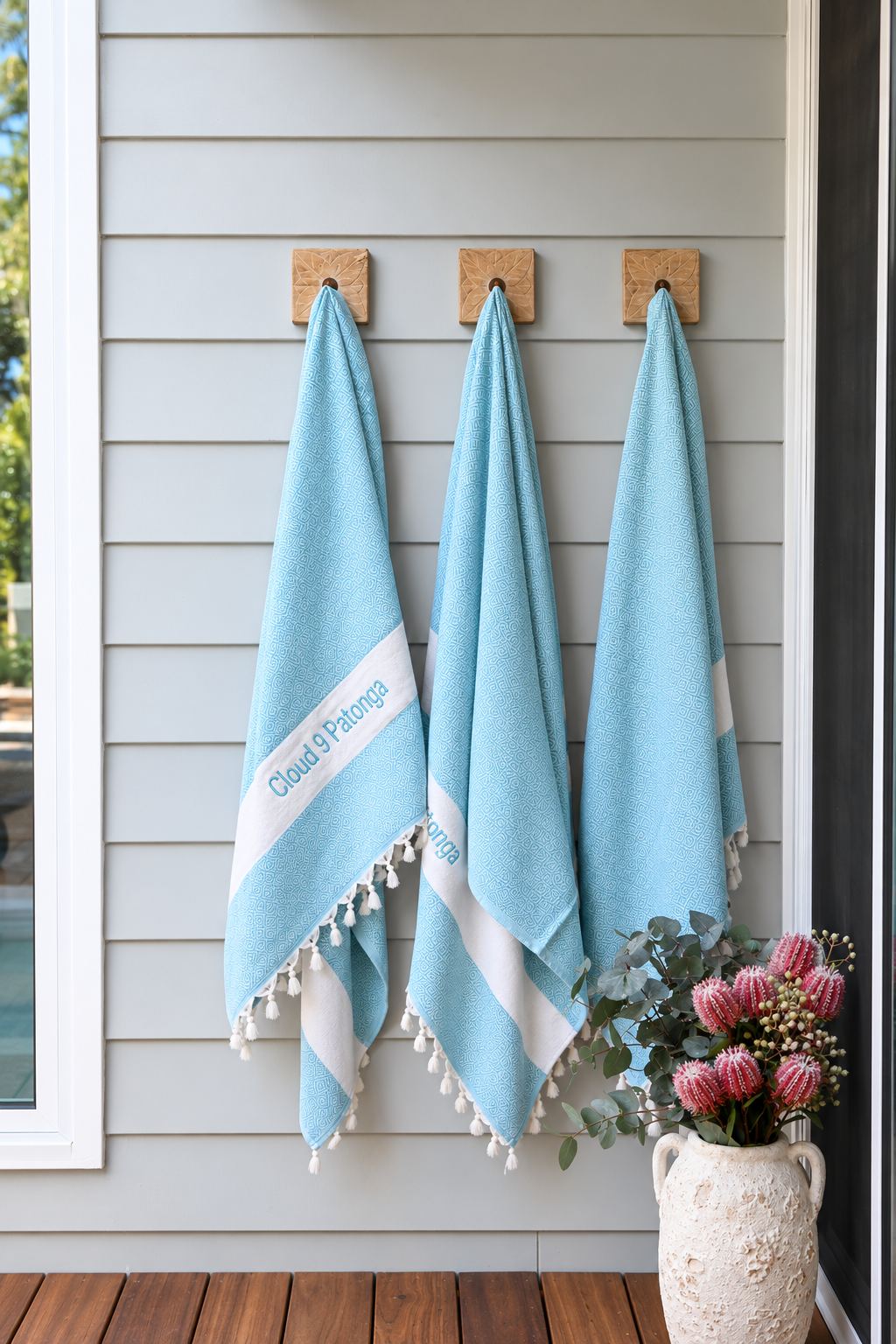 Striped beach towels on timber hooks beside the pool